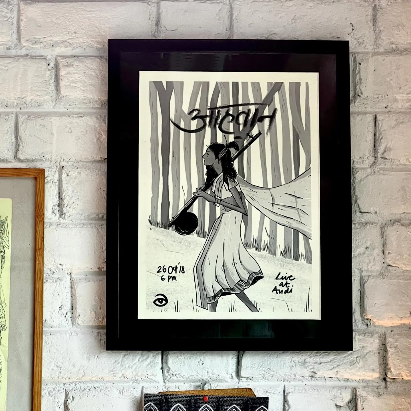 Framed Aahvaan gig poster hanging on a brick wall